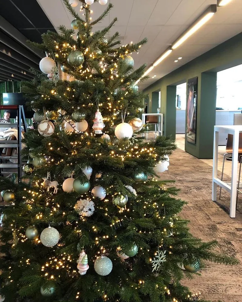 Opgetuigde kerstboom in een lange kantoorruimte